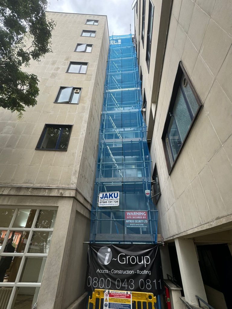 Access Tower Scaffolding by Jaku Scaffolding erected between two buildings in London, enclosed in blue safety netting.
